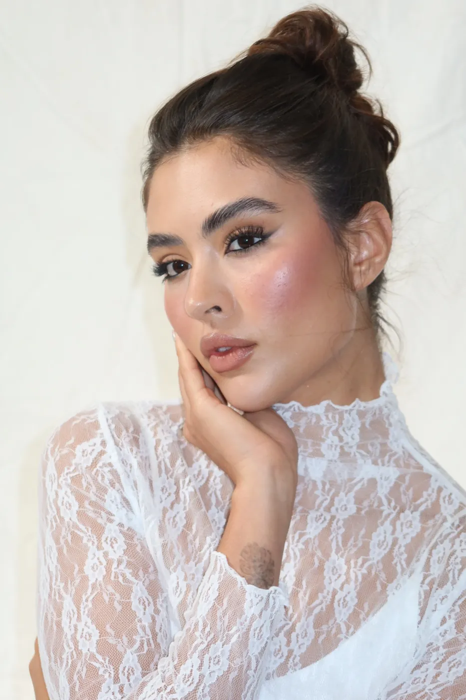 High lace neckline with a lifted lash and rosy blush