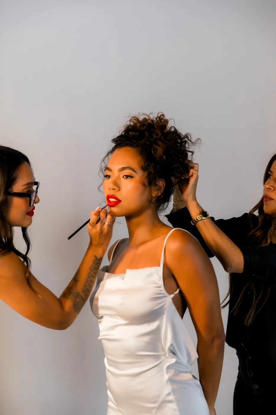 Two team artists styling a bride with a red lip